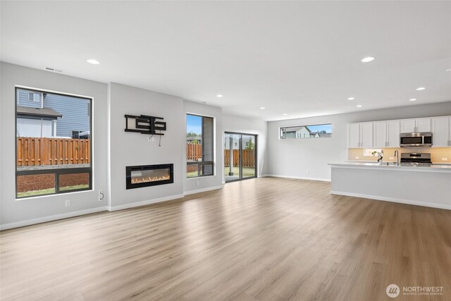 298 Hovey St, Buckley, WA 98321 - unfurnished living room with light wood-type flooring, a glass covered fireplace, and recessed lighting