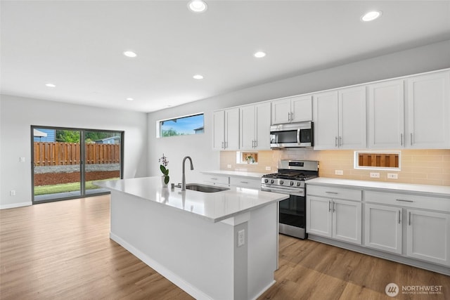 298 Hovey St, Buckley, WA 98321 - kitchen with appliances with stainless steel finishes, light wood-style flooring, decorative backsplash, recessed lighting, and a kitchen island with sink