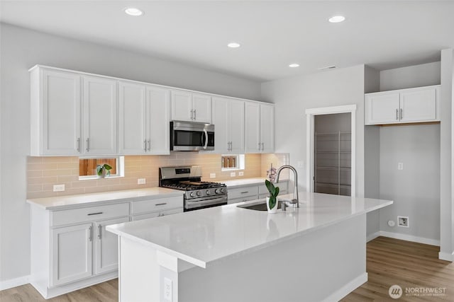 298 Hovey St, Buckley, WA 98321 - kitchen with appliances with stainless steel finishes, light wood-style floors, white cabinets, decorative backsplash, and recessed lighting