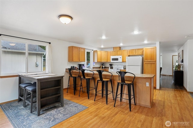 17230 Heather Ln SE, Yelm, WA 98597 - kitchen with white appliances, light wood-style floors, a kitchen breakfast bar, a peninsula, and plenty of natural light