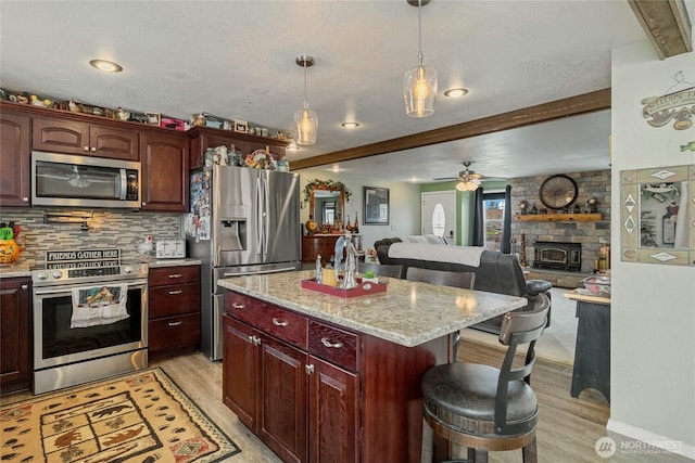 327 N Grape Dr, Moses Lake, WA 98837 - kitchen with appliances with stainless steel finishes, light wood-style floors, open floor plan, tasteful backsplash, and a breakfast bar