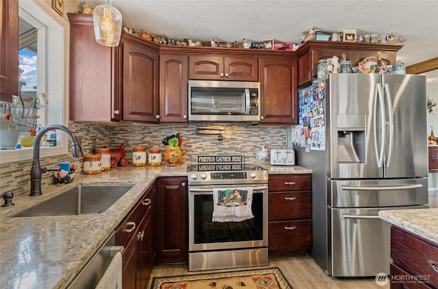 327 N Grape Dr, Moses Lake, WA 98837 - kitchen with appliances with stainless steel finishes, light stone counters, light wood-type flooring, and tasteful backsplash