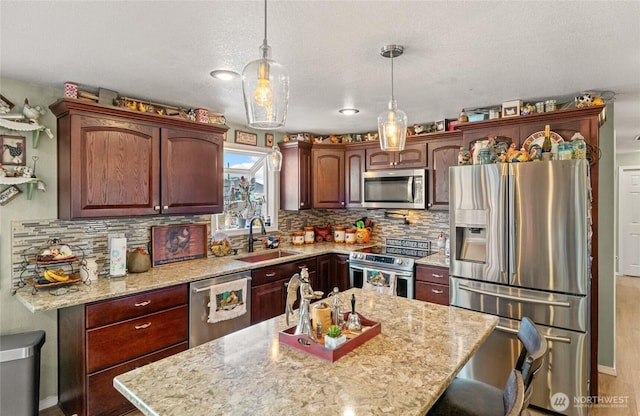 327 N Grape Dr, Moses Lake, WA 98837 - kitchen featuring appliances with stainless steel finishes, backsplash, pendant lighting, light stone countertops, and a textured ceiling