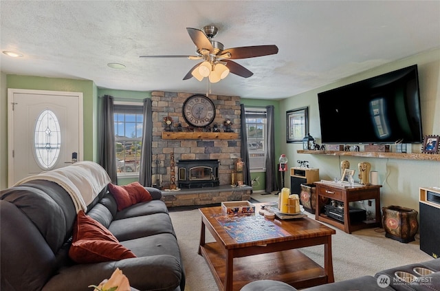 327 N Grape Dr, Moses Lake, WA 98837 - carpeted living area with healthy amount of natural light, ceiling fan, a textured ceiling, and a wood stove