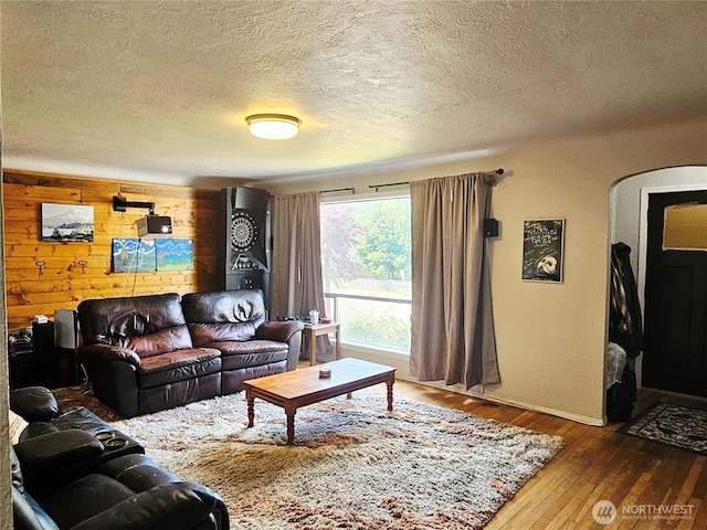 591 Division Ave, Morton, WA 98356 - living room with hardwood / wood-style flooring, a textured ceiling, wood walls, and arched walkways