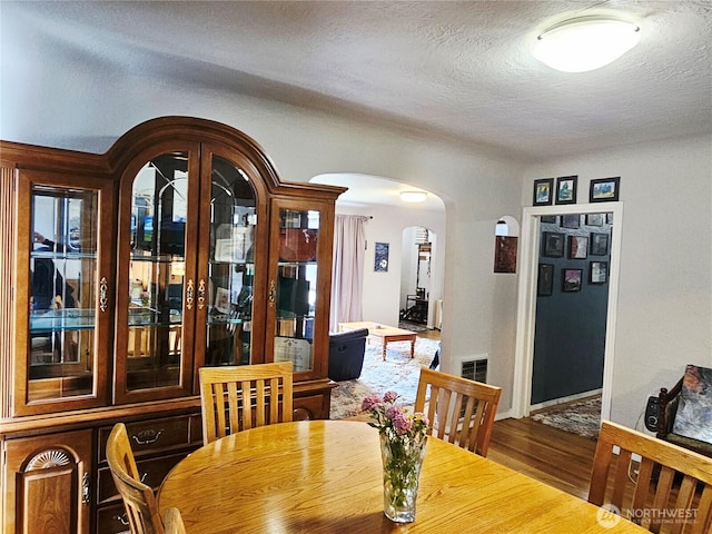 591 Division Ave, Morton, WA 98356 - dining space featuring arched walkways, wood finished floors, and a textured ceiling