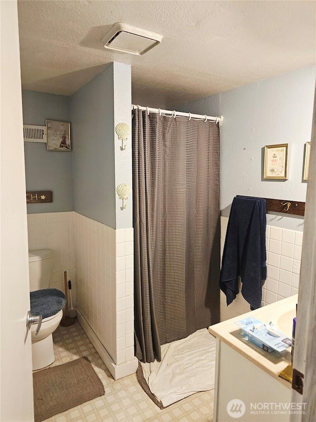 591 Division Ave, Morton, WA 98356 - full bathroom with tile patterned floors, tile walls, a shower with curtain, vanity, and a wainscoted wall