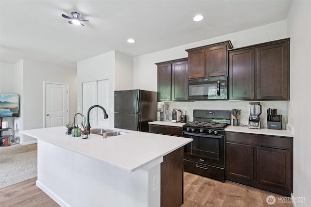 32803 Marguerite Ln, Sultan, WA 98294 - kitchen with black appliances, light wood-style flooring, light countertops, a center island with sink, and dark brown cabinetry