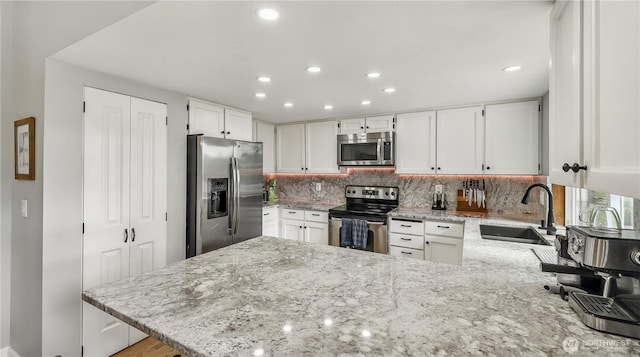 12350 SE 96th Pl, Renton, WA 98056 - kitchen featuring stainless steel appliances, a peninsula, light stone countertops, tasteful backsplash, and recessed lighting