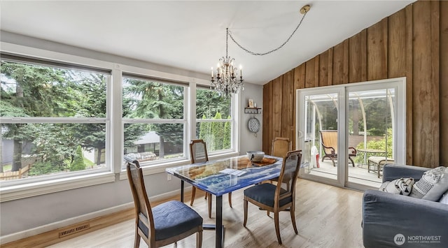 12350 SE 96th Pl, Renton, WA 98056 - dining space with healthy amount of natural light, a chandelier, lofted ceiling, wooden walls, and light wood-type flooring