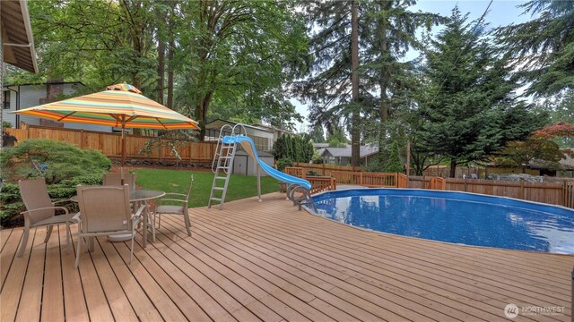 12350 SE 96th Pl, Renton, WA 98056 - view of pool with a water slide, outdoor dining area, a wooden deck, and a fenced backyard