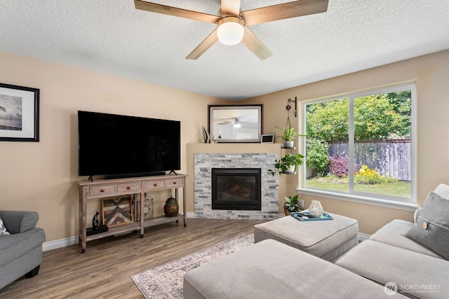 14908 NE 70th St, Vancouver, WA 98682 - living area with wood finished floors, a ceiling fan, a fireplace, and a textured ceiling