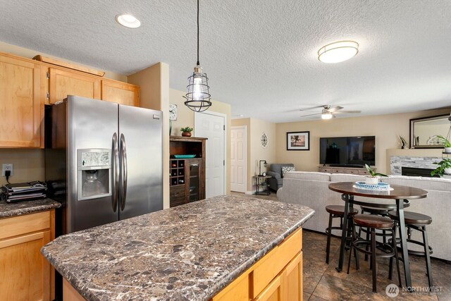 14908 NE 70th St, Vancouver, WA 98682 - kitchen with stainless steel fridge, a ceiling fan, a textured ceiling, light brown cabinetry, and a kitchen island