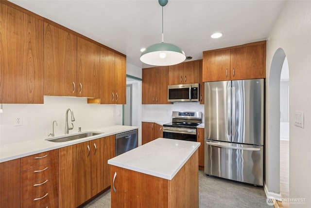 806 SW 126th St, Seattle, WA 98146 - kitchen featuring appliances with stainless steel finishes, brown cabinetry, arched walkways, light countertops, and a kitchen island