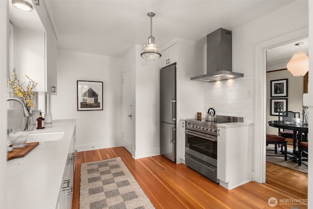 1157 N 78th St, Seattle, WA 98103 - kitchen with wall chimney exhaust hood, high end appliances, tasteful backsplash, white cabinetry, and light countertops