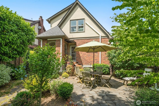 1157 N 78th St, Seattle, WA 98103 - view of front of property with brick siding, stucco siding, a patio area, a shingled roof, and outdoor dining space