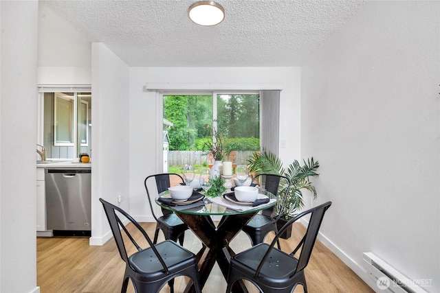 7509 E F St, Tacoma, WA 98404 - dining area featuring a textured ceiling, a baseboard radiator, and light wood-style flooring