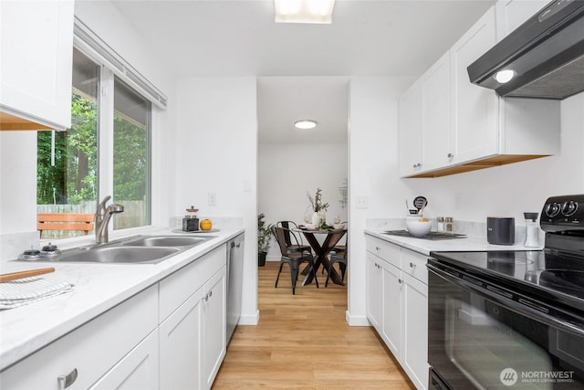 7509 E F St, Tacoma, WA 98404 - kitchen with black range with electric stovetop, exhaust hood, light wood-type flooring, light countertops, and white cabinets