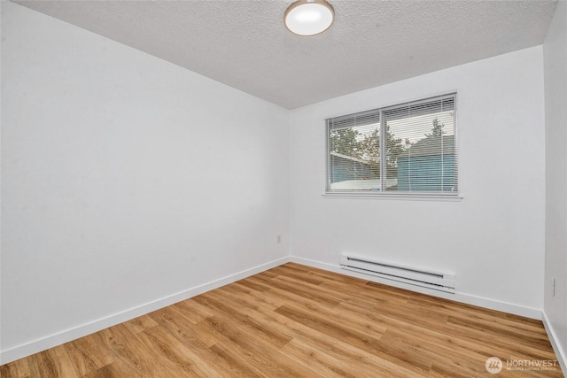 7509 E F St, Tacoma, WA 98404 - unfurnished room featuring a baseboard heating unit, light wood-style flooring, and a textured ceiling