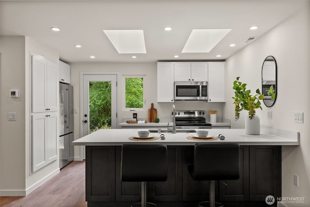 754 SW Oak Rd, Port Orchard, WA 98367 - kitchen with stainless steel appliances, a skylight, light countertops, a peninsula, and a kitchen breakfast bar