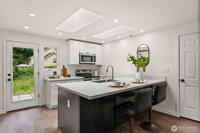 754 SW Oak Rd, Port Orchard, WA 98367 - kitchen featuring stainless steel appliances, a skylight, wood finished floors, light countertops, and white cabinets
