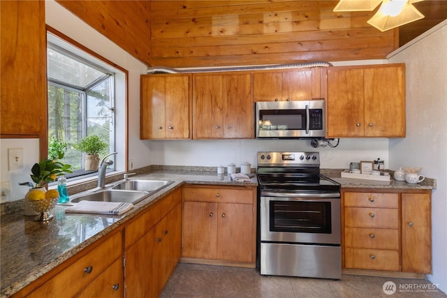 1681 E Saint Andrews Dr N, Shelton, WA 98584 - kitchen featuring stainless steel appliances, tile patterned floors, brown cabinetry, and stone countertops