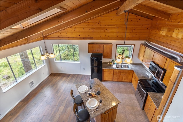 1681 E Saint Andrews Dr N, Shelton, WA 98584 - kitchen featuring a chandelier, stainless steel range with electric cooktop, freestanding refrigerator, brown cabinetry, and hanging light fixtures