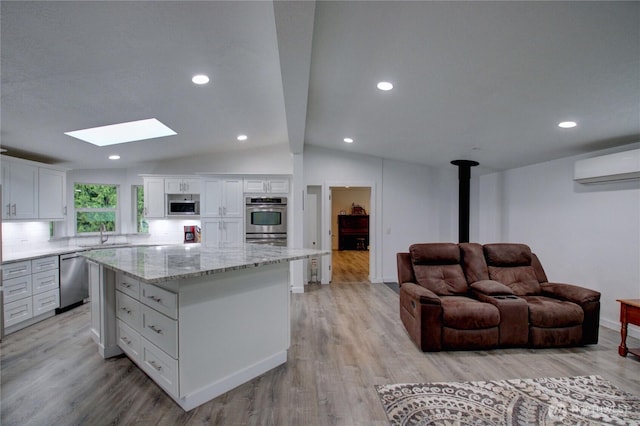 7493 State Route 9, Sedro Woolley, WA 98284 - kitchen with appliances with stainless steel finishes, a wall mounted air conditioner, a skylight, a wood stove, and white cabinetry