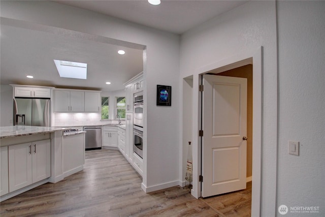 7493 State Route 9, Sedro Woolley, WA 98284 - kitchen with stainless steel appliances, a skylight, recessed lighting, white cabinetry, and light stone counters