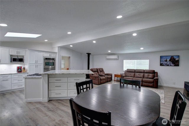 7493 State Route 9, Sedro Woolley, WA 98284 - dining area featuring a wood stove, a wall mounted AC, light wood-style floors, a skylight, and recessed lighting