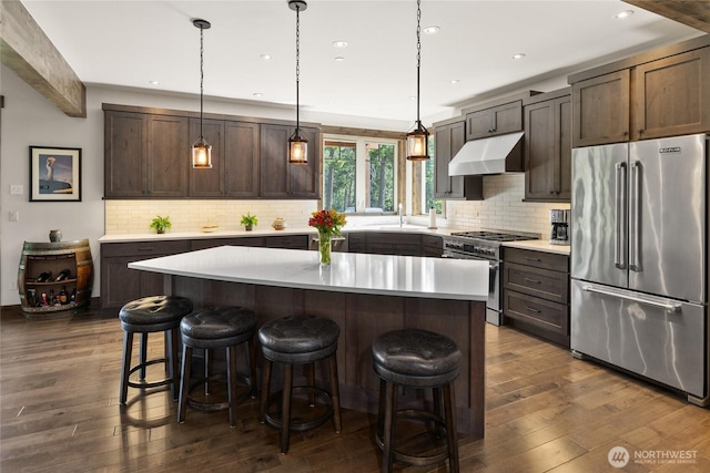 151 Miners Camp Way, Cle Elum, WA 98922 - kitchen with high end appliances, under cabinet range hood, dark wood-style floors, dark brown cabinets, and a kitchen breakfast bar