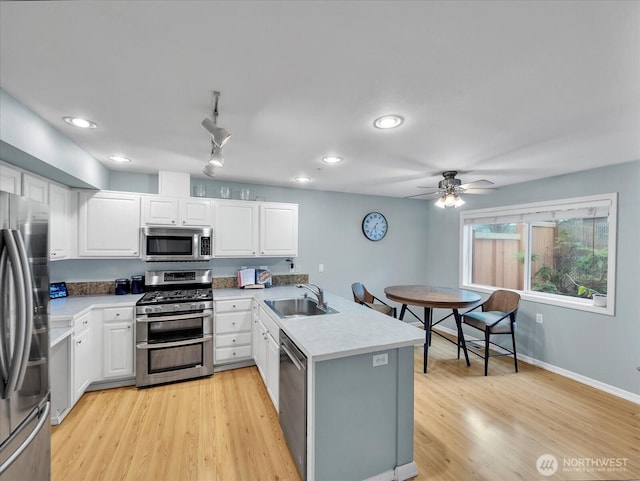 2218 S 336th St Unit 604, Federal Way, WA 98003 - kitchen with stainless steel appliances, a peninsula, white cabinets, light wood-style floors, and ceiling fan