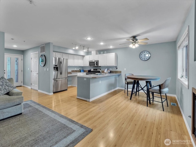 2218 S 336th St Unit 604, Federal Way, WA 98003 - kitchen featuring appliances with stainless steel finishes, a peninsula, light wood-style floors, open floor plan, and a breakfast bar