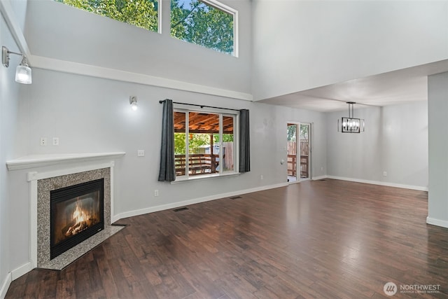 1407 196th St E, Spanaway, WA 98387 - unfurnished living room with a fireplace, a towering ceiling, a chandelier, and wood finished floors