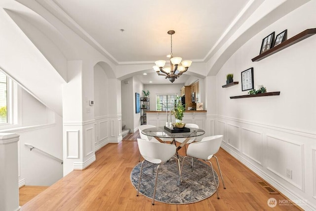 17815 80th Ave NE Unit C-1, Kenmore, WA 98028 - dining space featuring a chandelier, a decorative wall, arched walkways, a wainscoted wall, and light wood-style floors