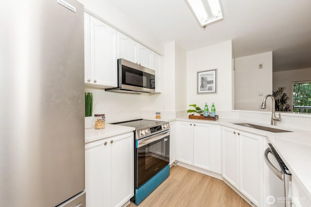 18505 SE Newport Way Unit E221, Issaquah, WA 98027 - kitchen with stainless steel appliances, white cabinets, light wood finished floors, and light countertops
