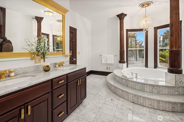 1214 Warren Ave N, Seattle, WA 98109 - bathroom featuring marble look tile flooring, double vanity, a bath, decorative columns, and a chandelier