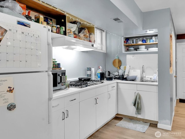 4715 19th Ave NE, Seattle, WA 98105 - kitchen featuring stainless steel appliances, open shelves, light wood-style floors, white cabinets, and light countertops