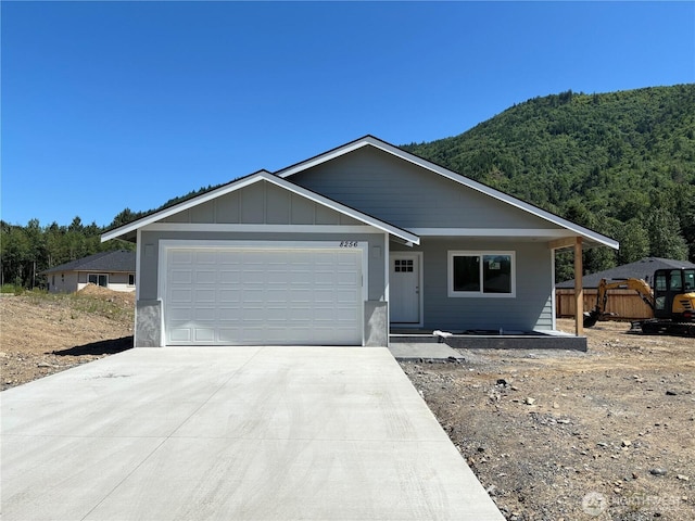 8256 Gold Run Dr, Maple Falls, WA 98266 - ranch-style home with driveway, an attached garage, a view of trees, and board and batten siding