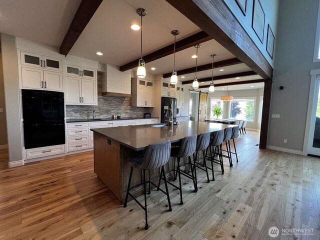 12003 Summit Haven Pl, Yakima, WA 98908 - kitchen with black appliances, premium range hood, beamed ceiling, light wood finished floors, and a spacious island