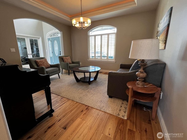 12003 Summit Haven Pl, Yakima, WA 98908 - living room with arched walkways, a tray ceiling, ornamental molding, light wood-style floors, and french doors