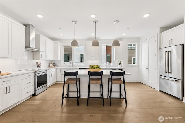 12257 137th Pl NE Unit 2901, Redmond, WA 98052 - kitchen featuring stainless steel appliances, wall chimney exhaust hood, a breakfast bar, white cabinetry, and recessed lighting