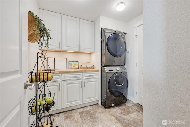 26908 NE Bird St, Duvall, WA 98019 - laundry room with stacked washing machine and dryer, stone finish flooring, and cabinet space