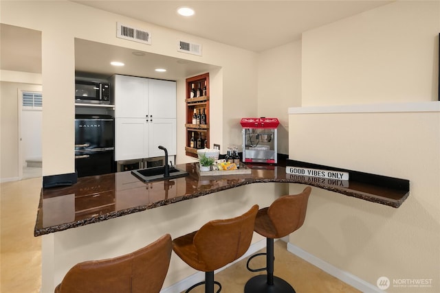 7440 SE 32nd St, Mercer Island, WA 98040 - kitchen featuring white cabinetry, dark stone counters, a breakfast bar, and recessed lighting