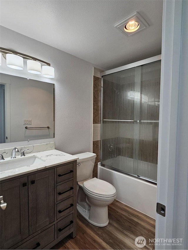 509 S 323rd Pl Unit 15E, Federal Way, WA 98003 - full bathroom featuring wood finished floors, vanity, enclosed tub / shower combo, a textured ceiling, and a textured wall