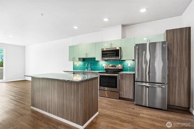 1085 103rd Ave NE Unit 217, Bellevue, WA 98004 - kitchen featuring appliances with stainless steel finishes, dark wood-style flooring, tasteful backsplash, a kitchen island, and recessed lighting