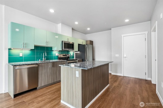 1085 103rd Ave NE Unit 217, Bellevue, WA 98004 - kitchen with stainless steel appliances, a kitchen island, wood finished floors, dark stone countertops, and recessed lighting