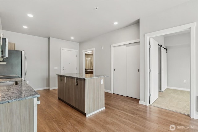 1085 103rd Ave NE Unit 217, Bellevue, WA 98004 - kitchen with freestanding refrigerator, a center island, light wood-style floors, a barn door, and recessed lighting