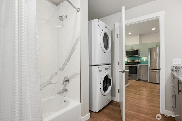 1085 103rd Ave NE Unit 217, Bellevue, WA 98004 - full bathroom featuring stacked washer / dryer, shower / bathtub combination with curtain, wood finished floors, and vanity