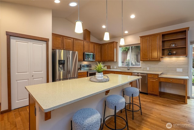 700 Twin Brooks Dr, Mount Vernon, WA 98273 - kitchen featuring stainless steel appliances, brown cabinetry, light wood-type flooring, tasteful backsplash, and vaulted ceiling